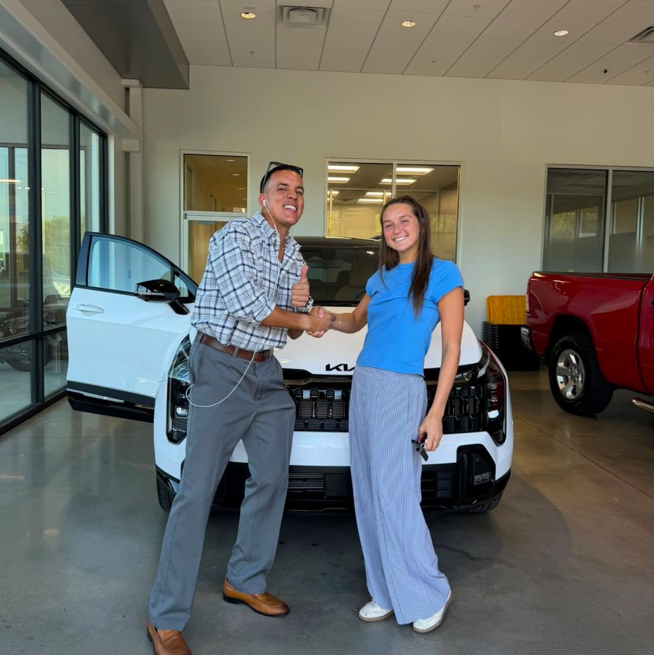 Mario shaking hands with a client in front of her new SUV