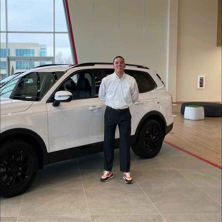 Mario's Facebook profile photo: Mario beside a white SUV on a showroom floor